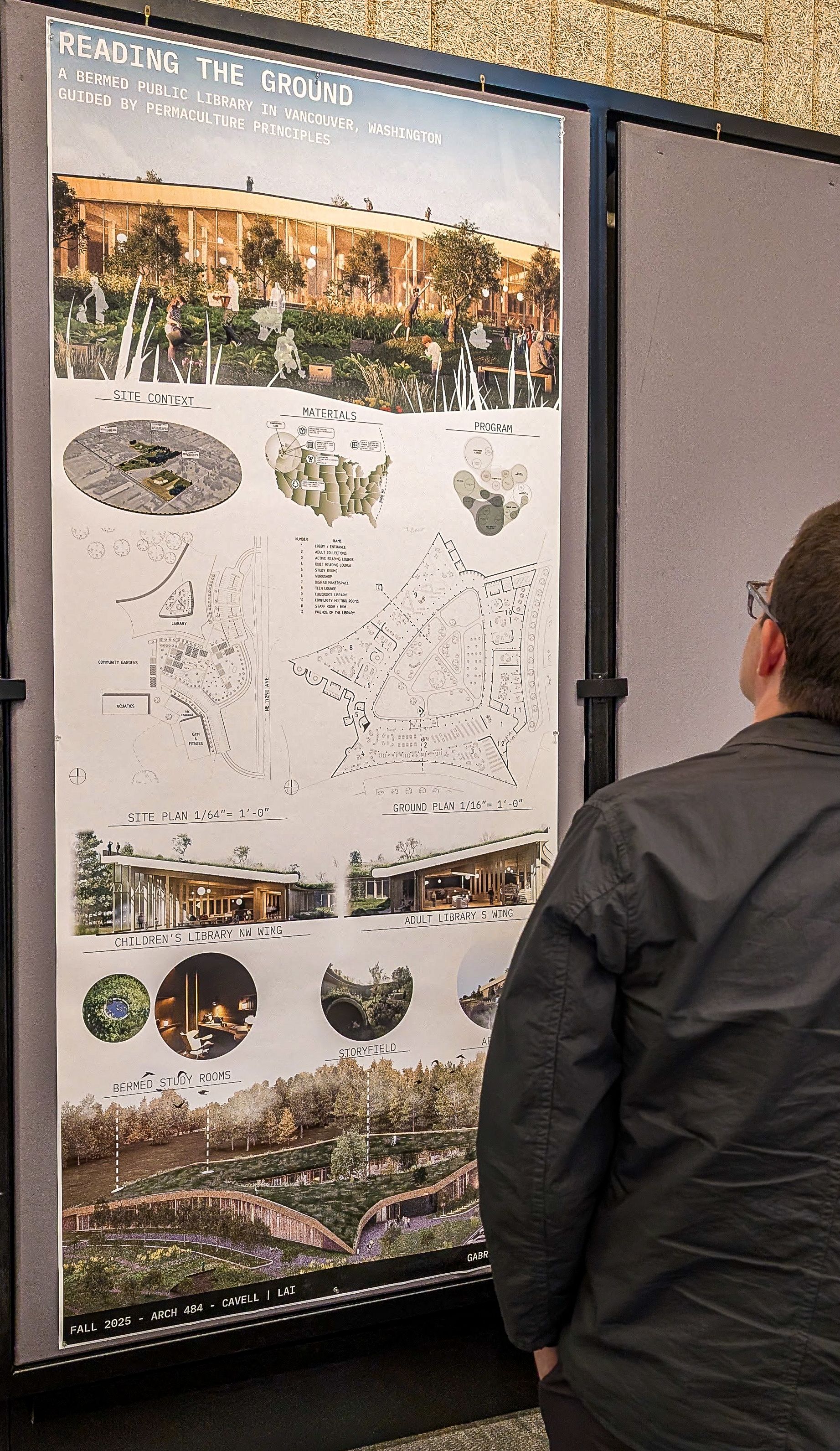A man reviews one of the final posters tacked to the wall. 