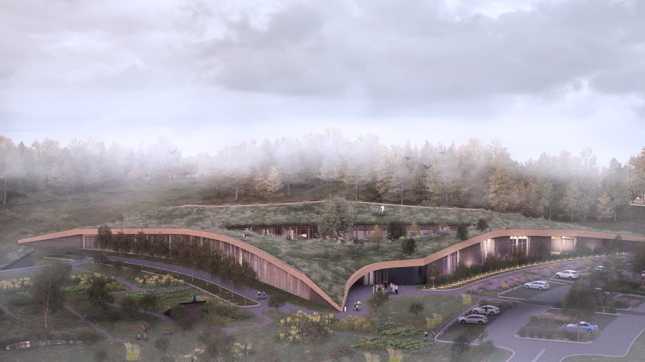 Rendering of a building tucked into the landscape. Grass and trees are on top of the curved roof. 