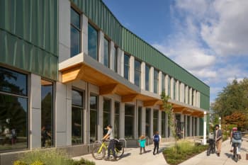Exterior of the Holgate Library designed by Bora architects. People are walking and biking past.