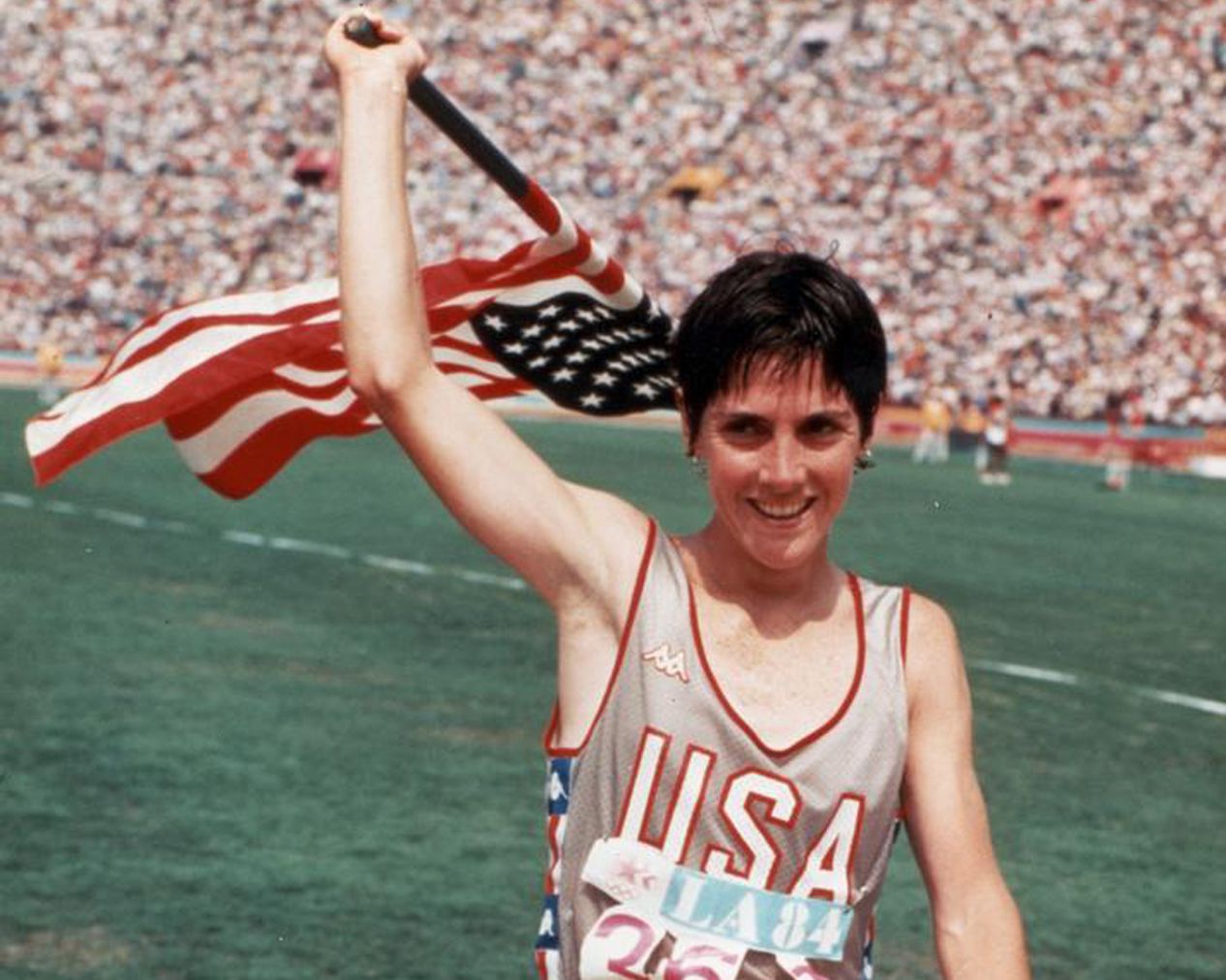 An historic photo from the 1970s of female athlete raising the U.S. flag after a victory in her event at Hayward Field.
