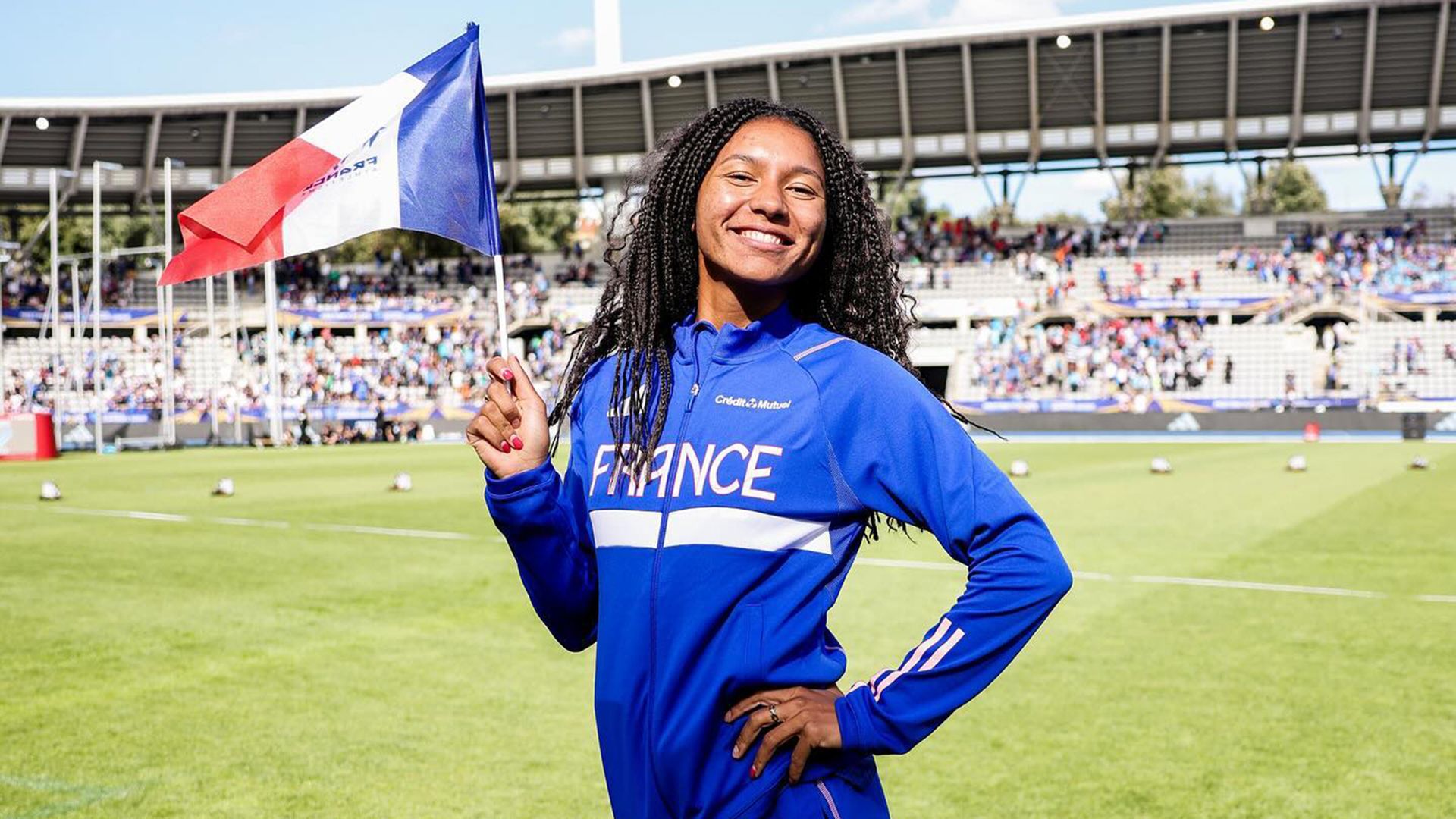 Shana Grebo standing outside holding the flag of France.
