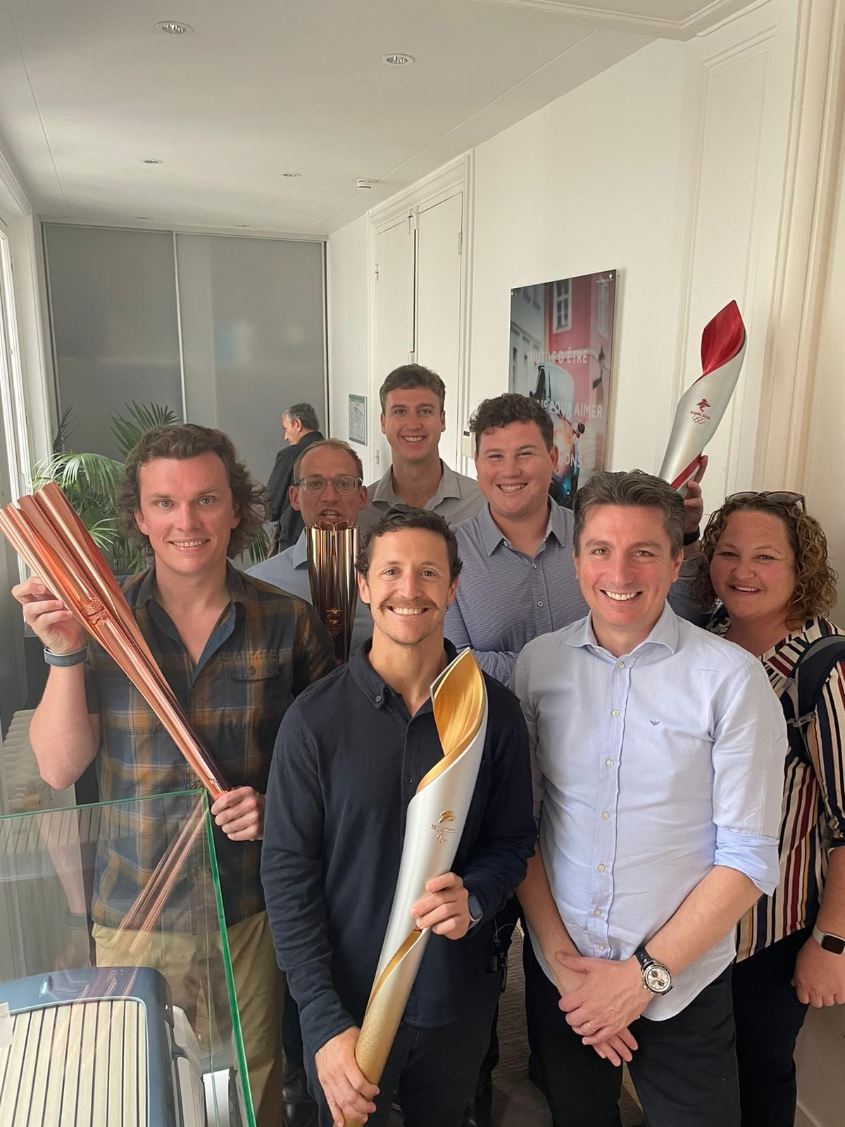 Several students are smiling at the camera and holding replicas of the Olympic torch.