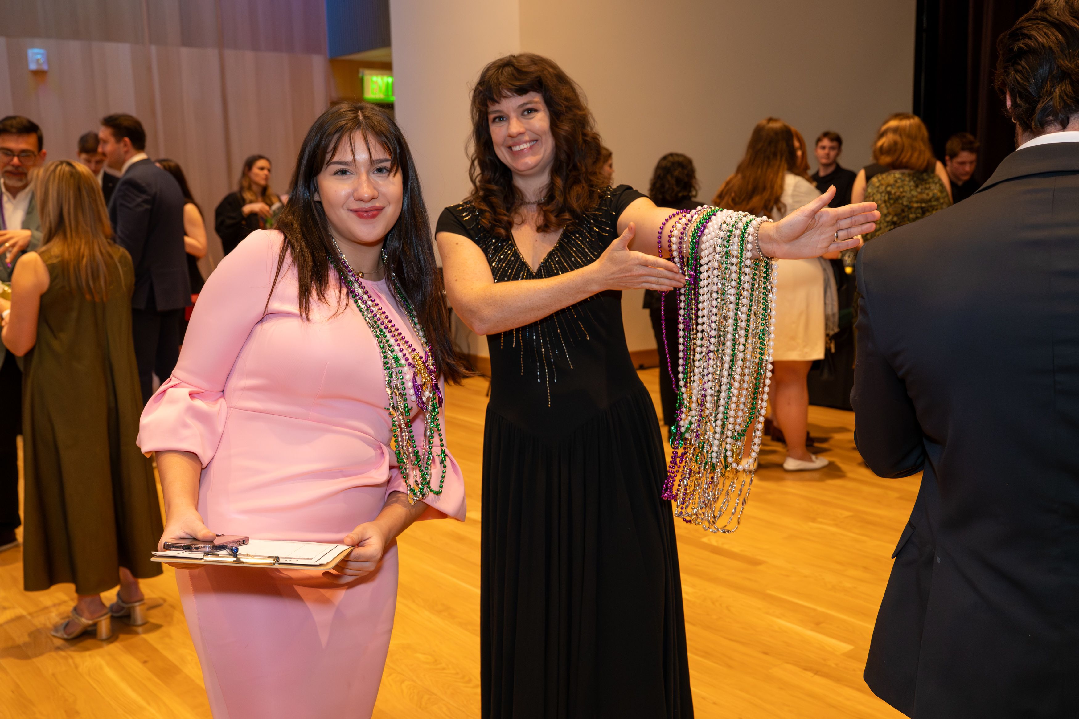 Two female law students display the mardi gras necklaces available for purchase as a fundraiser. 