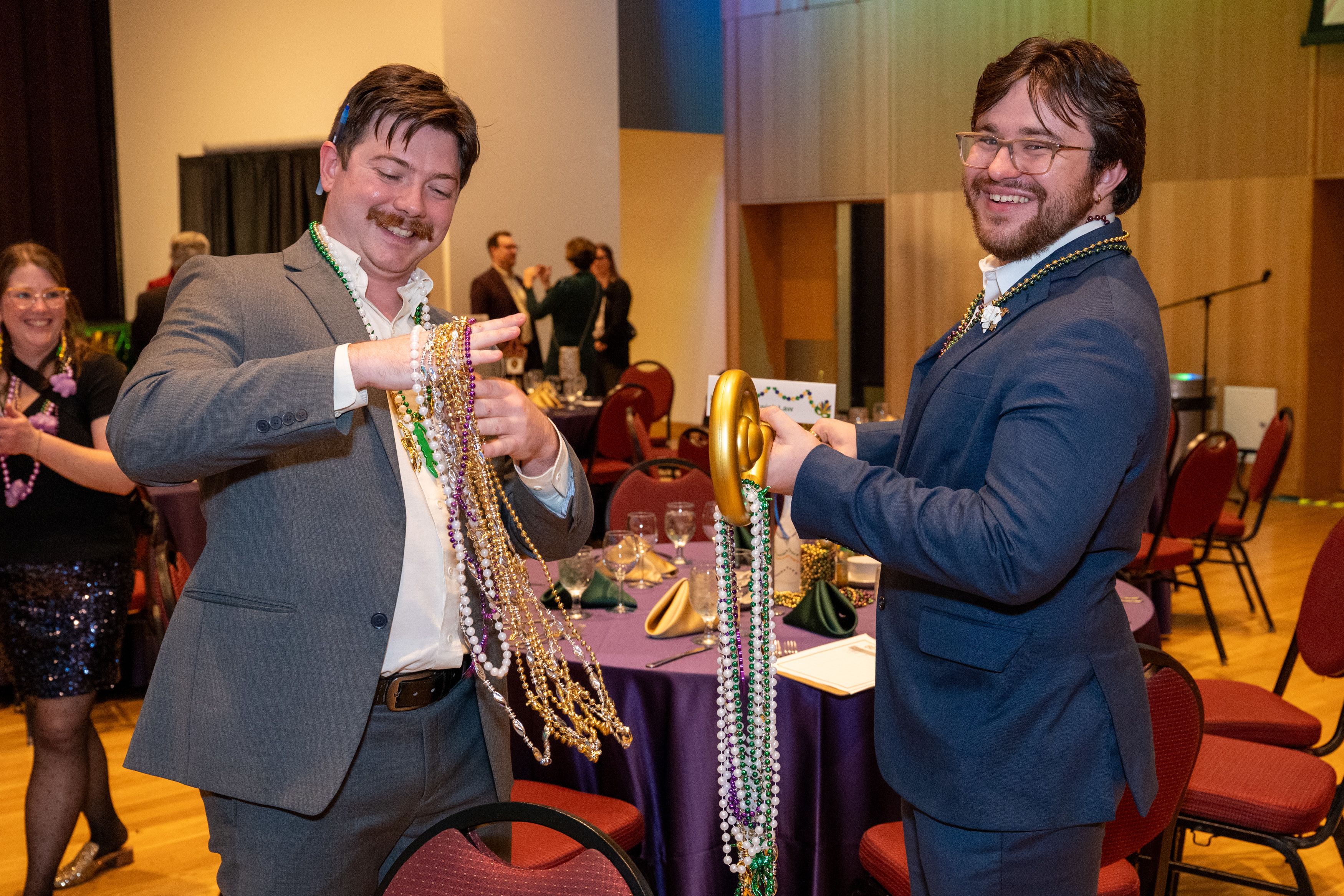 Two students with lots of strings of mardi gras beads. 
