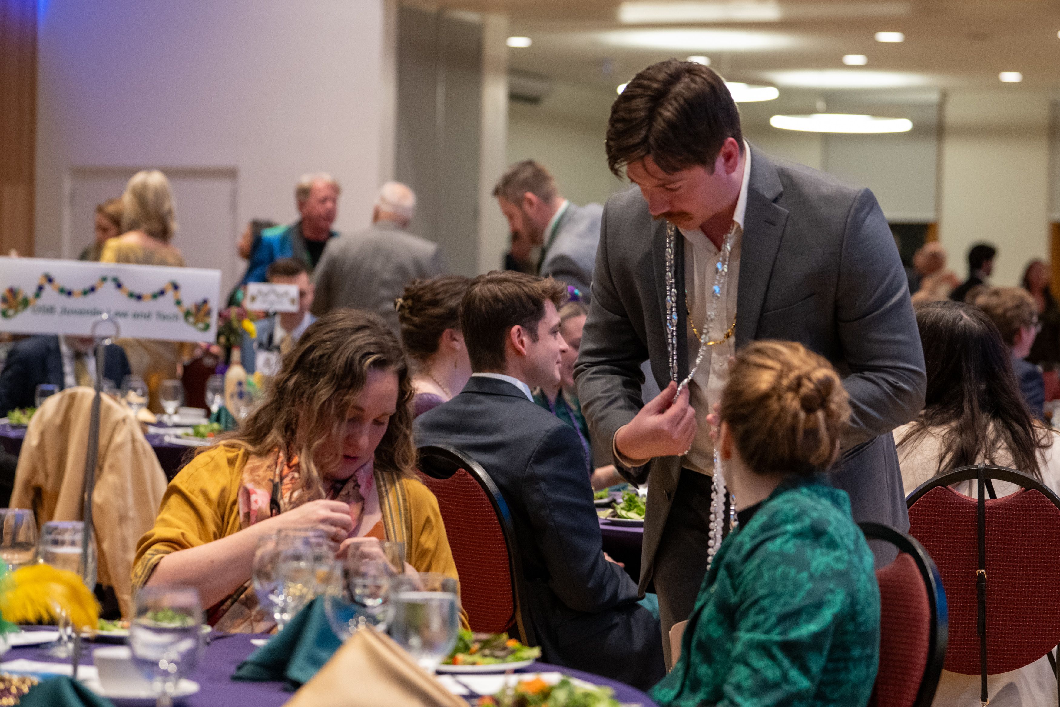 Student selling madri law bead necklaces to guests at a table. 
