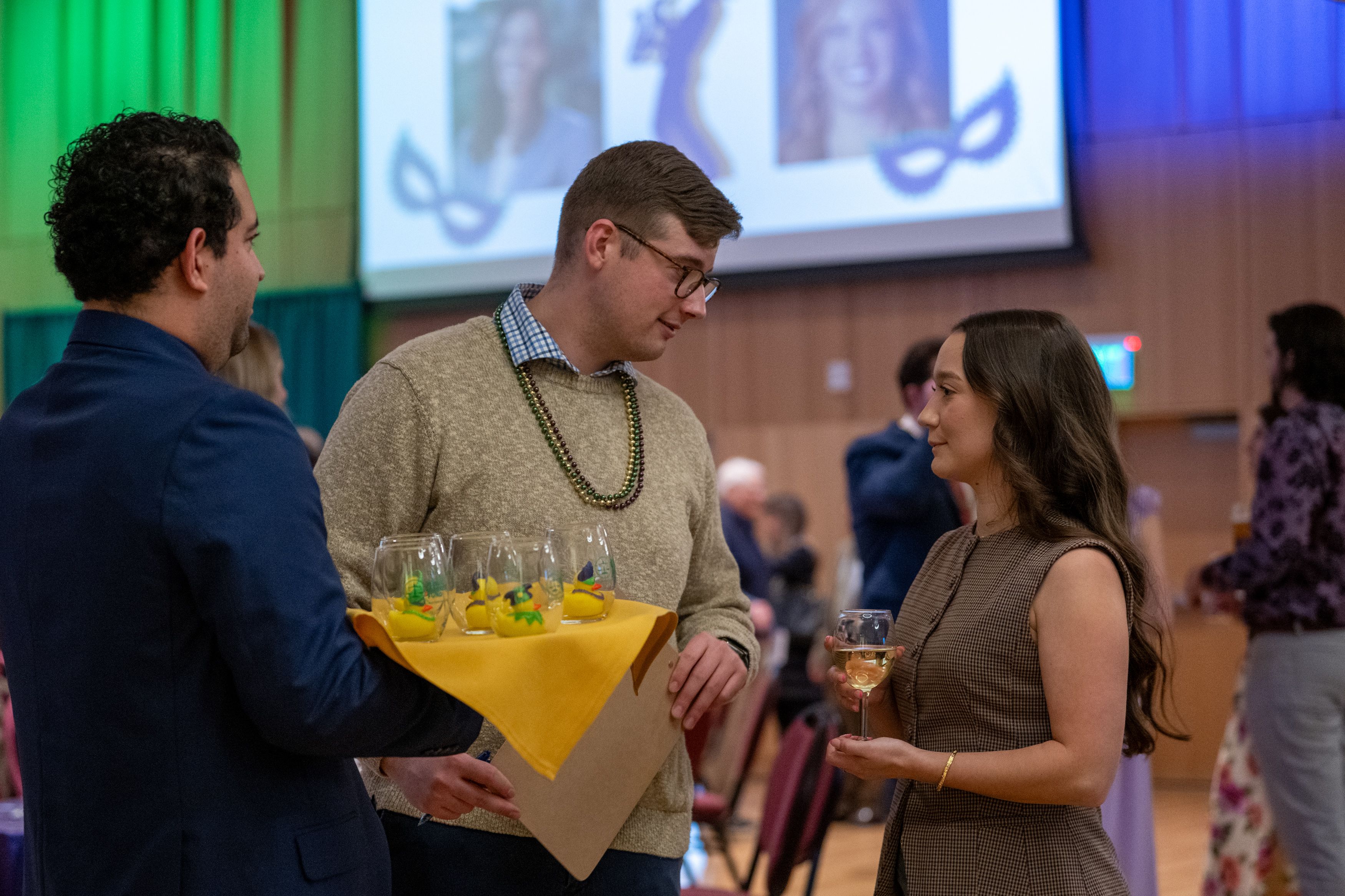 Law students offering duck raffle glasses to a guest. 